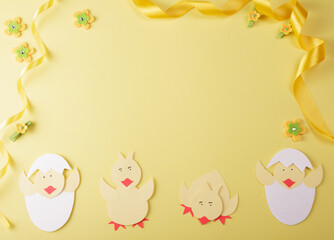 Bright composition of handmade chickens, golden ribbon and empty space for an inscription on a yellow