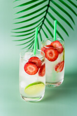 Refreshing Summer Drink with Strawberry and Lime in Glasses on green Background Tasty Healthy Non Alchogolic Beverage with Ice Cube