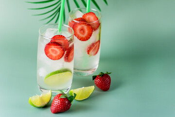 Refreshing Summer Drink with Strawberry and Lime in Glasses on green Background Tasty Healthy Non Alchogolic Beverage with Ice Cube