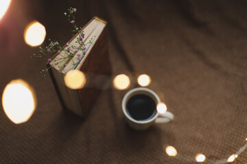 A book with flowers and cup of coffee on dark background top view