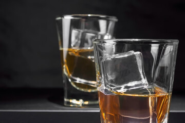 Close up of a glass with an alcoholic drink with ice on a black background. Selective focus.