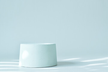 The podium is light blue in color with a geometric figure made of concrete. A scene with a cement display case. Minimalistic background. Presentation of cosmetics.