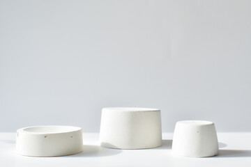Three white catwalks with a geometric figure made of concrete. A scene with a cement display case. Minimalistic background. Presentation of cosmetics.