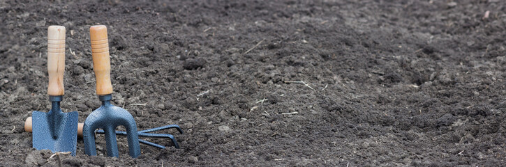 Hand garden tools on a background of black soil, tools for the gardener.