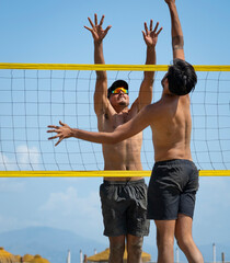 young men playing beach volleyball on a sunny day