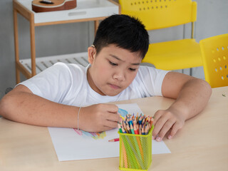 Redundant Children An Asian man is concentrating on coloring wood during art lessons in a classroom for children with disabilities.
