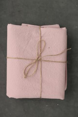 Obraz na płótnie Canvas photo of natural and ecological washed cotton fabric sample in light pink colour on dark background rewound with sack thread