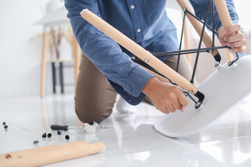 Young man doing DIY work, assembling furniture at home.