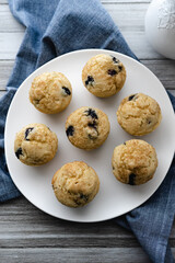 Overhead view of a plate of freshly baked gluten-free dairy-free blueberry muffins on a blue napkin.