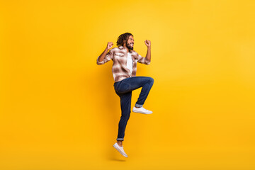 Fototapeta na wymiar Full length body size photo of man jumping high gesturing like lottery winner laughing isolated on vibrant yellow color background