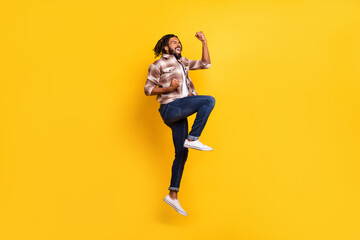 Fototapeta na wymiar Full length body size photo of man jumping high gesturing like winner overjoyed isolated on vivid yellow color background