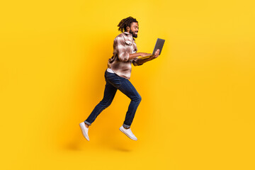 Fototapeta na wymiar Full length body size photo of man jumping high working on laptop for start-up isolated on vibrant yellow color background