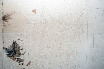 Structure of dirty white wall with dilapidated plaster