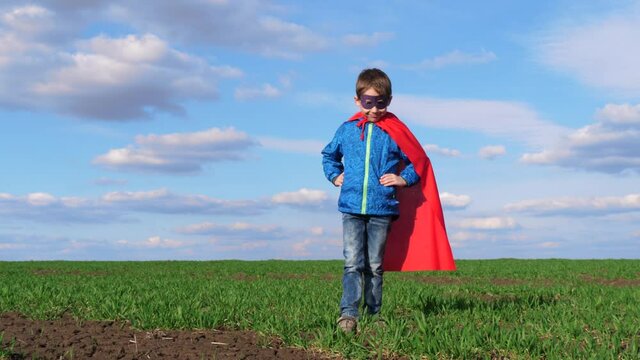 Happy funny kid. A boy in a mask and a red cape portrays a strong hero. A superhero