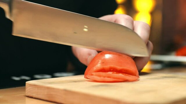 Slicing of a tomato in the restaurant kitchen