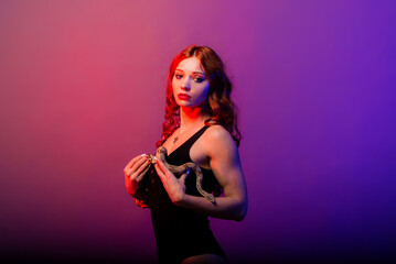 Beautiful young redhead woman with a snake with a fashionable perfect makeup. Studio shot