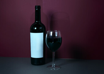 a glass of red wine on a burgundy background with a bottle of wine in the background. stylish wine advertising. suitable for advertising a wine restaurant. mokap. banner.