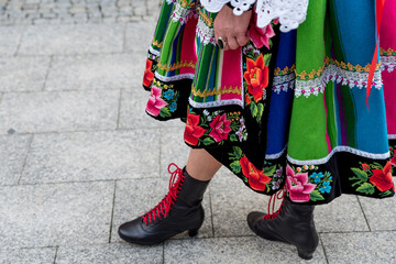 Woman dressed in polish national folk costume from Lowicz region. Close up of traditional colorful striped Lowicz folk dress, shoes and embroidery