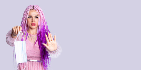 Caucasian girl in fashionable clothes on a gray background. Afro style woman stretching a mask, Copy space.