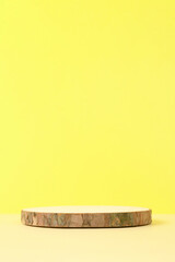 Round wooden podium on beige and yellow background for product.