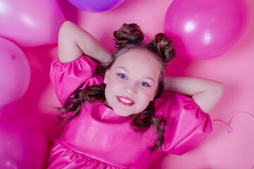 Obraz na płótnie Canvas attractive brunette girl model with pink make up and in pink leather dress near colorful balloons on pink background.concept of joy, party, birthday.