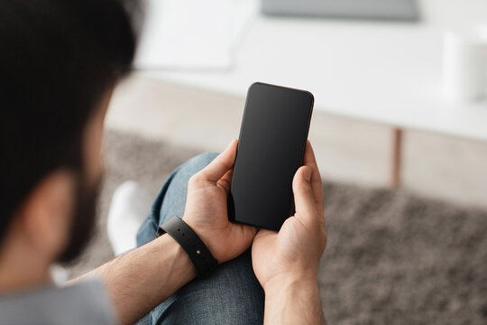 Mockup image with man holding cellphone with blank black screen, messaging or surfing internet