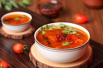 Tomato rasam curry hot spicy soup South Indian cuisine prepared using Indian spices, tomato tamarind , chili, cumin. Traditional vegetarian dish rice onam sadhya Kerala, Tamil Nadu, India Sri Lanka.