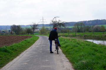 Ein Radfahrer steht auf einem Radweg in den Leinewiesen bei Alfeld Leine