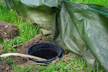 a bucket set in the ground on a toad protection fence