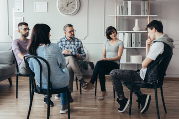 Group of people of different ages sits in a circle during a meeting with a professional therapist