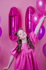 sweet brunette girl with pink make up and in pink leather dress. near colorful balloons in shape of number eleven. on pink background.concept of joy, party, birthday celebration.