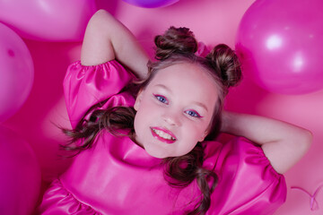 Obraz na płótnie Canvas attractive brunette girl model with pink make up and in pink leather dress near colorful balloons on pink background.concept of joy, party, birthday.