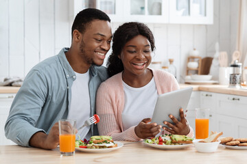 Obraz na płótnie Canvas Online Shopping. Millennial Black Couple In Kitchen Using Digital Tablet During Breakfast