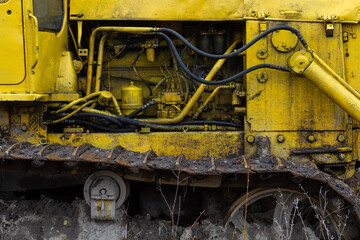 A close-up photo of the pneumatic system of a crawler forestry tractor. Yellow metal body of the tractor, part of the caterpillar.