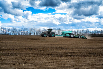 sowing work in the field in spring. Tractor with seeder