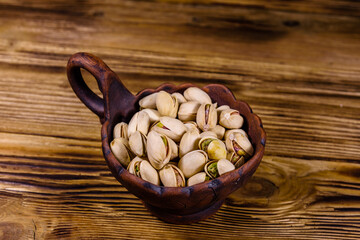 Ceramic bowl with pistachio nuts on a wooden table