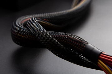 Cable snake skin. Black braided wires in bundle on black background. Braided Sleeving. Data line...