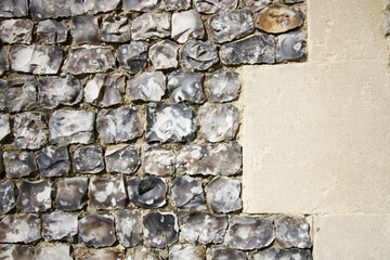 Wall built of grey flint beside cream cement with copyspace