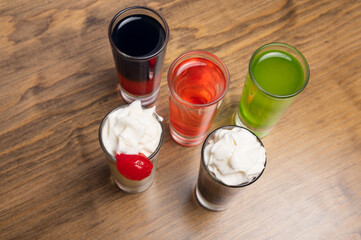Colorful alcoholic shots in wooden background. Alcohol shots on table bar. Mixology concept