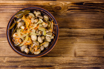 Canned mushrooms with carrot and onion in a ceramic bowl. Top view