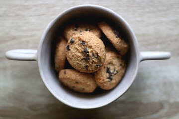 Bowl of chocolate chip cookies on wooden table. Flat lay.