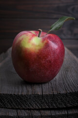 Alone red sweet apple on a textured wooden background