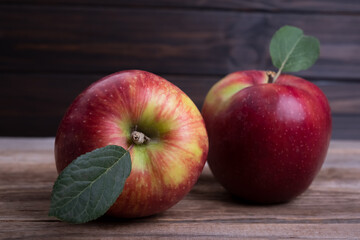 Two red sweet apples on a textured wooden background