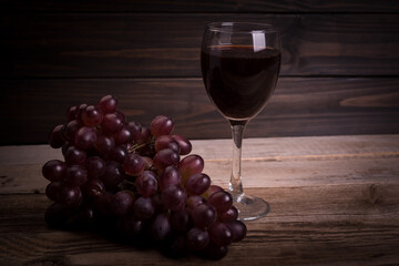 Glass with wine and grapes oon old wooden background
