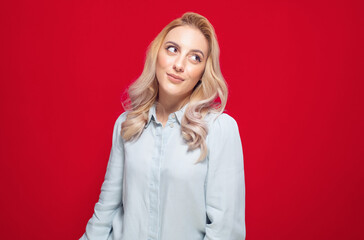 Smirking face expression of a woman, isolated on red background. Pretty girl smiling in an irritatingly smug, conceited