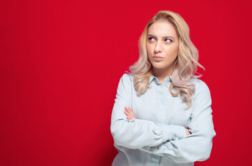 Annoyed young woman, isolated on red background. Displeased girl with arms crossed