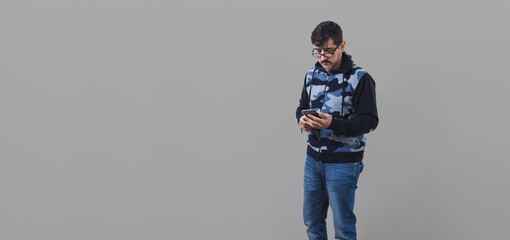 Panorámica de hombre con lentes enviando mensajes de texto desde su teléfono móvil. Retrato con...
