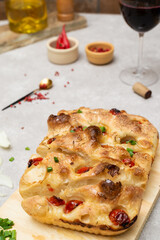 Focaccia at marble table, rosemary  spices and sweet tomato, parchment paper and wood with olive oil and red wine