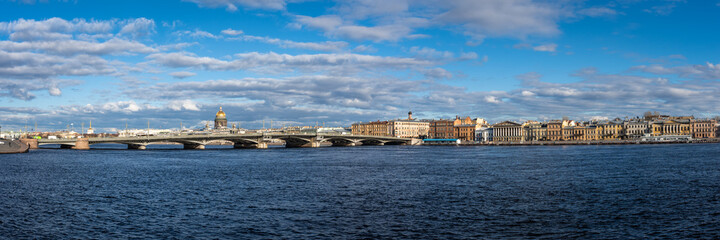 Fototapeta na wymiar Amazing Panorama of St. Petersburg, Russia. River Neva granite embankment. Sunny spring day. On the horizon are famous historical buildings on white clouds background. View from 