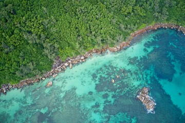 Drone field of view of turquoise blue waters meeting green forest Praslin, Seychelles.